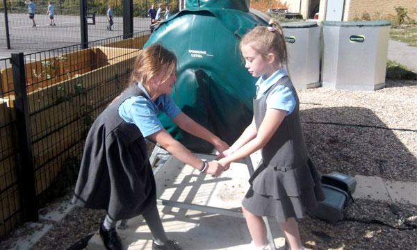 Two girls turning the handle on a Ridan Composting machine